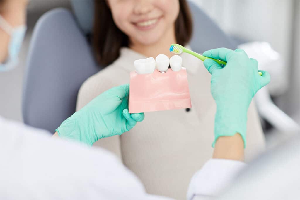 Dentist showing woman how to clean teeth