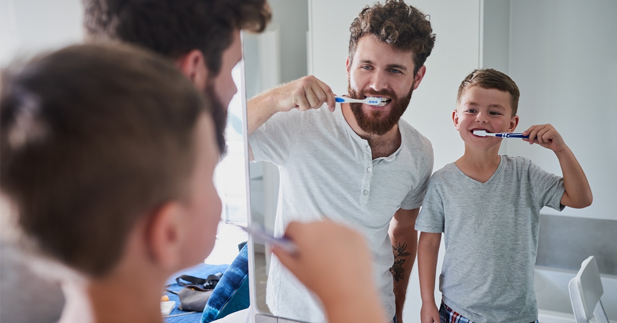 man and boy brushing teeth in mirror